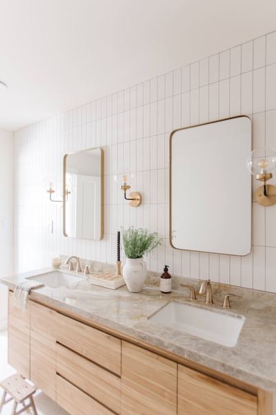 Bathroom vanity in white oak with a quartzite countertop, brass sconces, a brass-framed mirror and fine pinstriped wall panelling