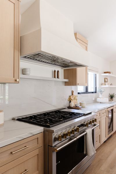 Kitchen with white oak cabinetry, a stainless range under a custom hood, marble countertops and open shelving